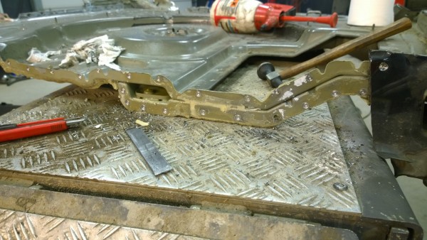 Golf trunk floor being drilled and chiseled from a larger piece.